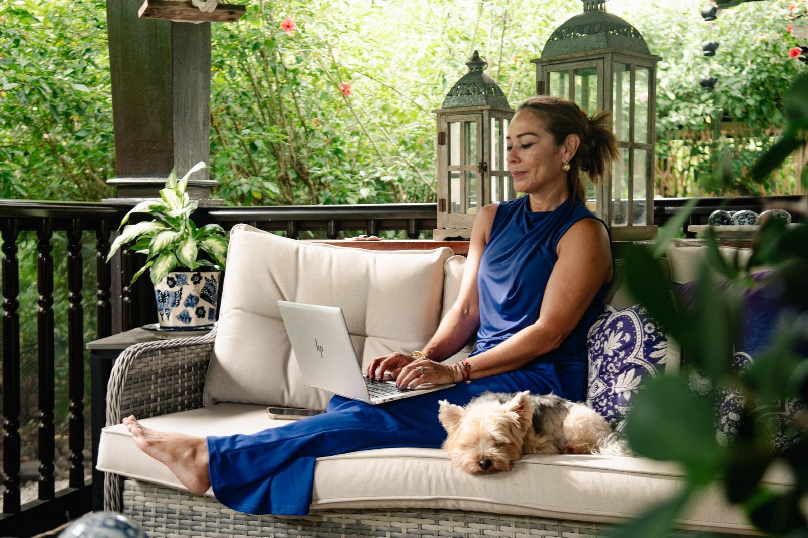 Karla trabajando con su laptop en la terraza, con su perrito al lado